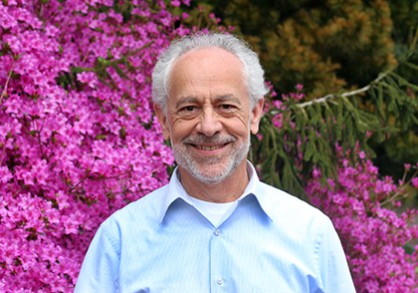man standing in front of a pink blooming bush