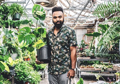 Hilton Carter in a greenhouse holding a potted plant