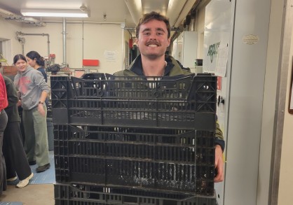 Student holding crates of bulbs