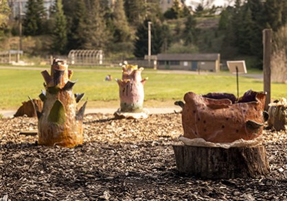 three colorful ceramic sculptures placed in a bare garden bed
