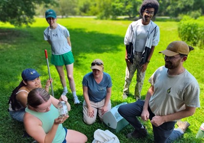 group of studetns look at jars with insects